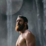 man with beard under waterfall