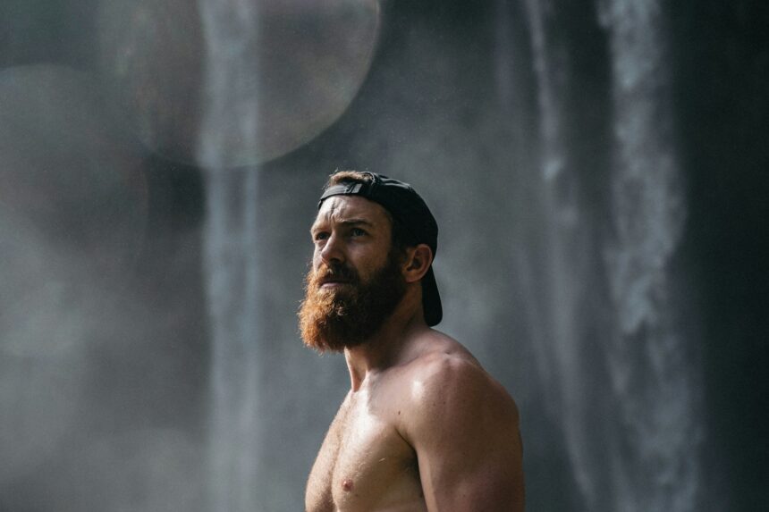 man with beard under waterfall