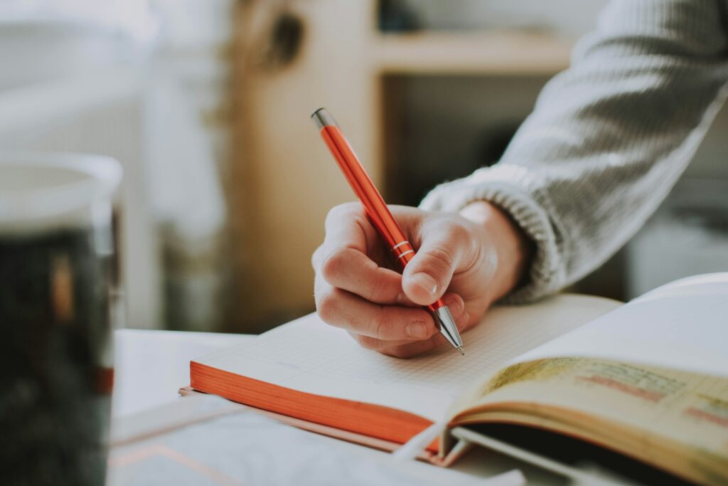 men journaling with orange pen