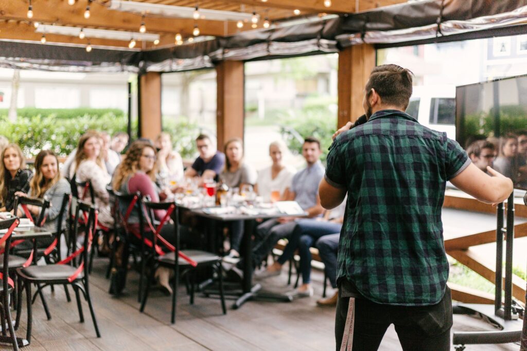 man talking with mic to a room of people