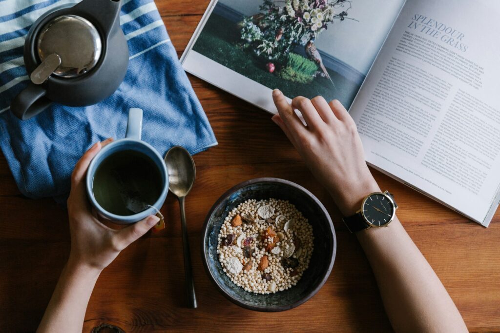 man eating at a table reading book and eating food